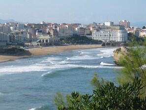 A coastal cityscape with a beach, waves, and buildings. - Rental two-room apartment Anglet center (Anglet)