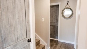 A hallway with wooden flooring, a door, and a staircase leading to another room. - Luxe Havelock Stay - Very Clean - Near MCAS Cherry Point - Cabana + Fire Pit (Havelock)