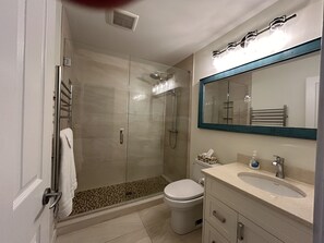 Een bad/douchecombinatie, een haardroger, handdoeken