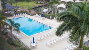A swimming pool with lounge chairs and umbrellas, surrounded by palm trees and a fence. - Fort Myers Beach Area 7327 - 311 (Fort Myers Beach)
