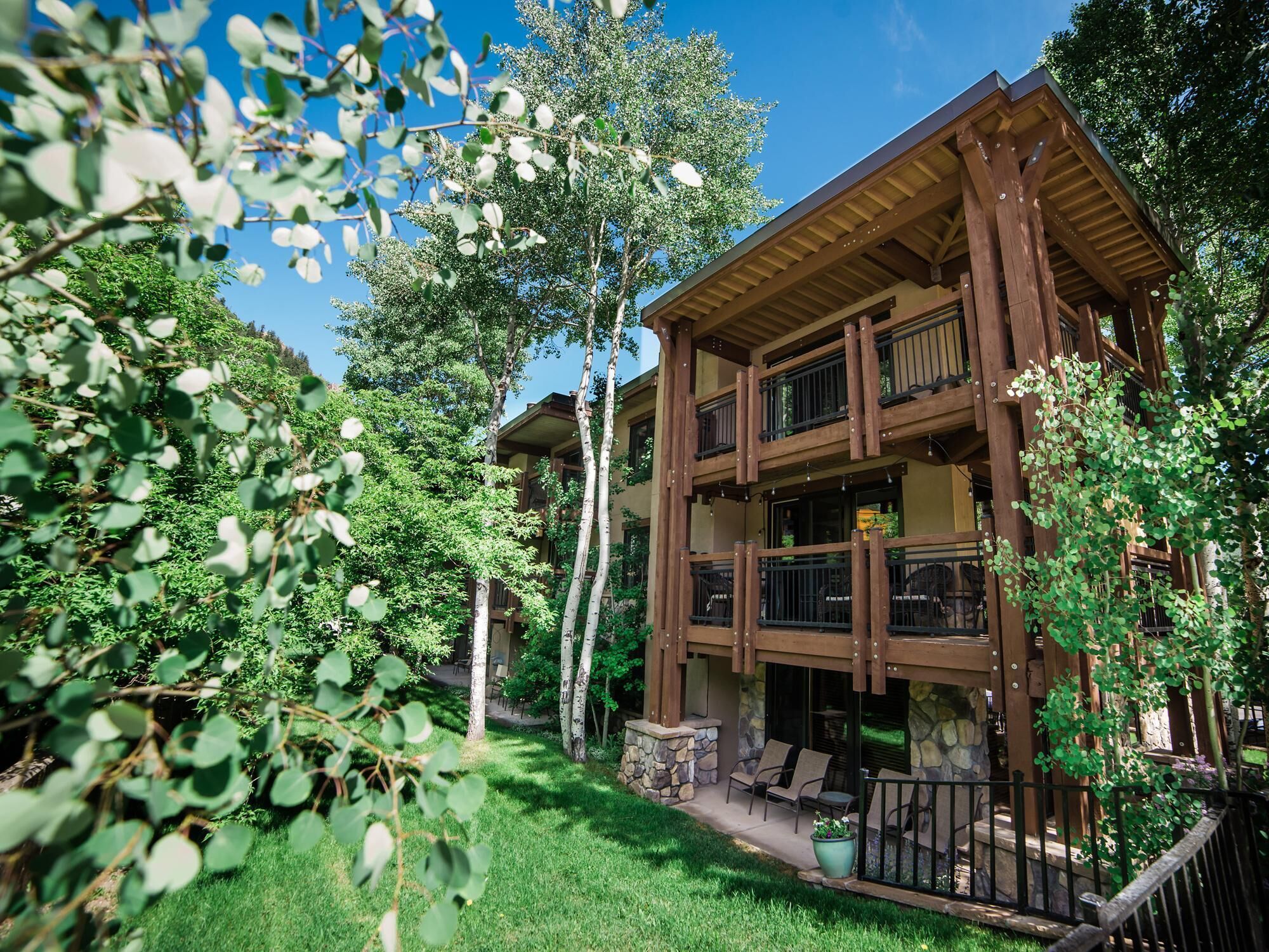 Un edificio de madera de varios pisos con balcones, rodeado de abundante vegetación y árboles.