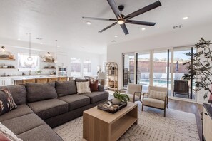 A modern living room with a sectional sofa, a coffee table, and a ceiling fan. - New Home | Private Pool, Hot Tub & Desert Views (Washington)