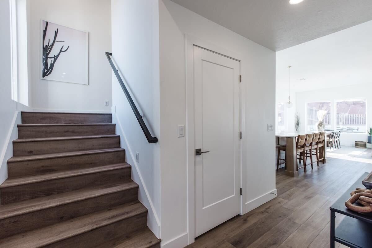 Un escalier menant à une salle à manger, avec une porte blanche et une œuvre d’art moderne accrochée au mur.