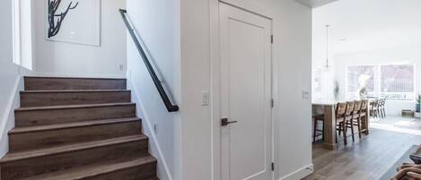 A staircase leading to a dining area with a white door and a modern art piece on the wall.