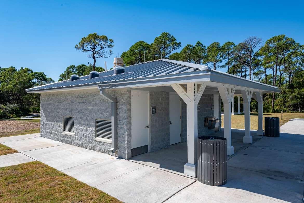 A small, single-story building with a stone facade, a covered patio area, and a solar panel on the roof.