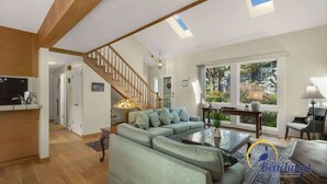 Ein geräumiges Wohnzimmer mit einem grünen Sofa, einem Couchtisch und einer Treppe, die in einen anderen Raum führt.