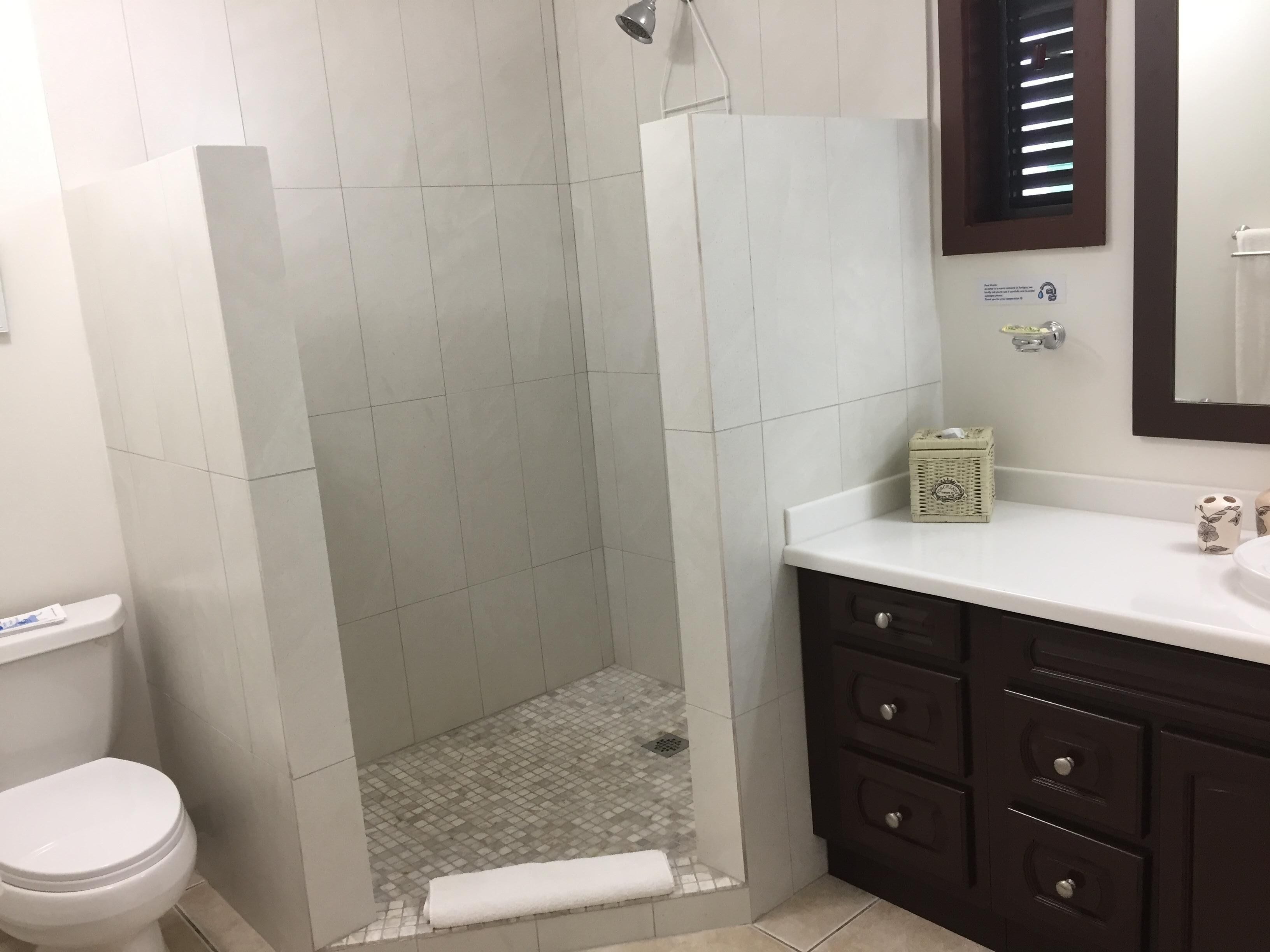 Een badkamer met douche, toilet en een wastafel met lades.