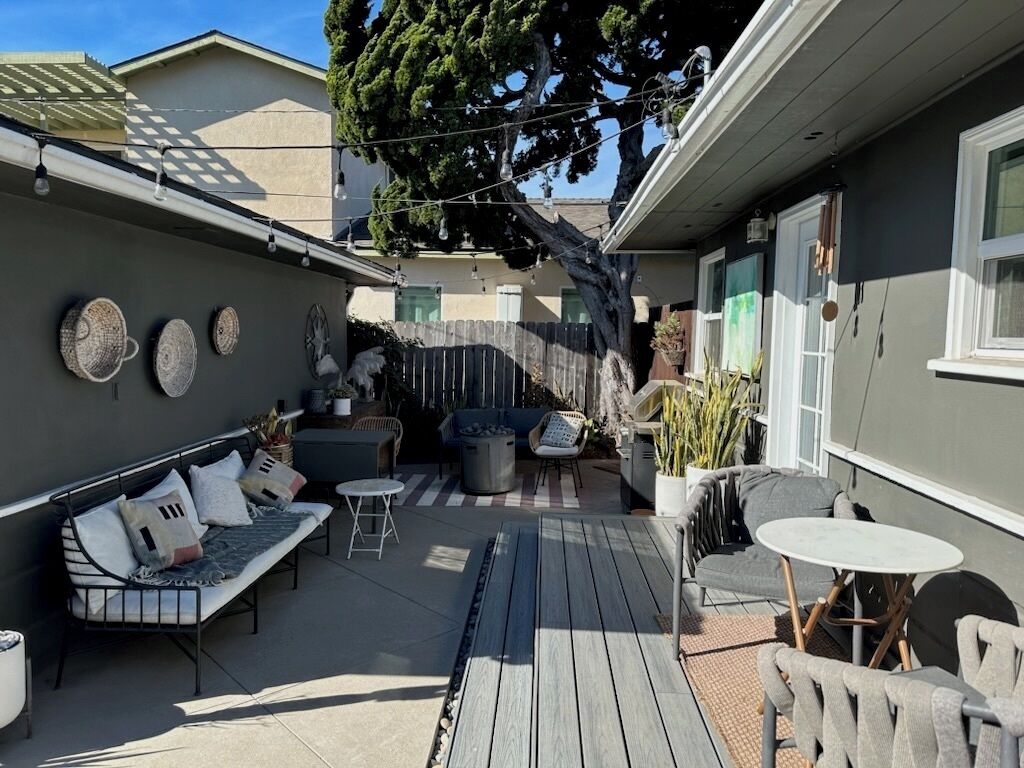 A patio with outdoor seating, a table, and a potted plant.