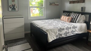 Ein Schlafzimmer mit Bett, Schminktisch, Fenster und Deckenventilator.