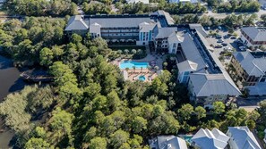 An aerial view of a hotel with multiple buildings, a swimming pool, and surrounding greenery. - 2 BR/2.5 BA condo/Redfish Village/Pool/Walk to beach/Beach chairs/umbrella (Santa Rosa Beach)