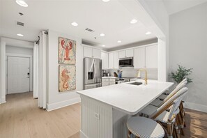 A modern kitchen with white cabinetry, a large island, stainless steel appliances, and decorative wall art.
