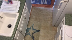 A kitchen with a sink, cabinets, and a starfish design on the floor. - Milepost 9 KDH Condo Oceanside (Kill Devil Hills)