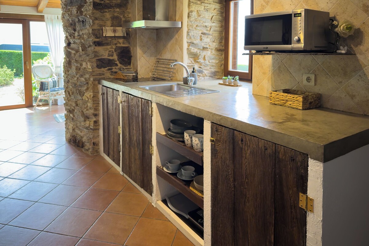 A kitchen with a stone wall, a built-in microwave, and a sink.
