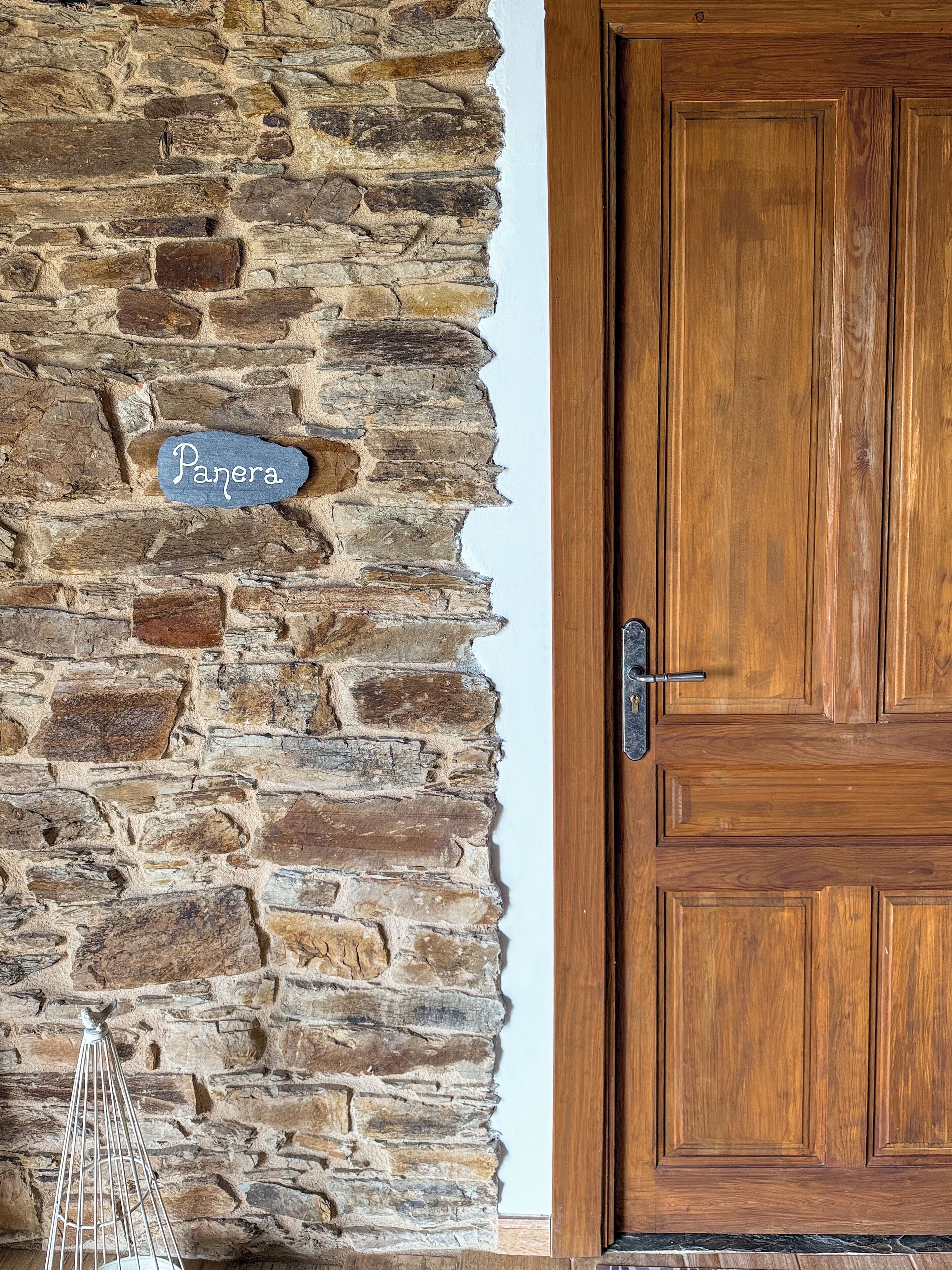 Un mur de pierre avec une enseigne indiquant « Panera » et une porte en bois.