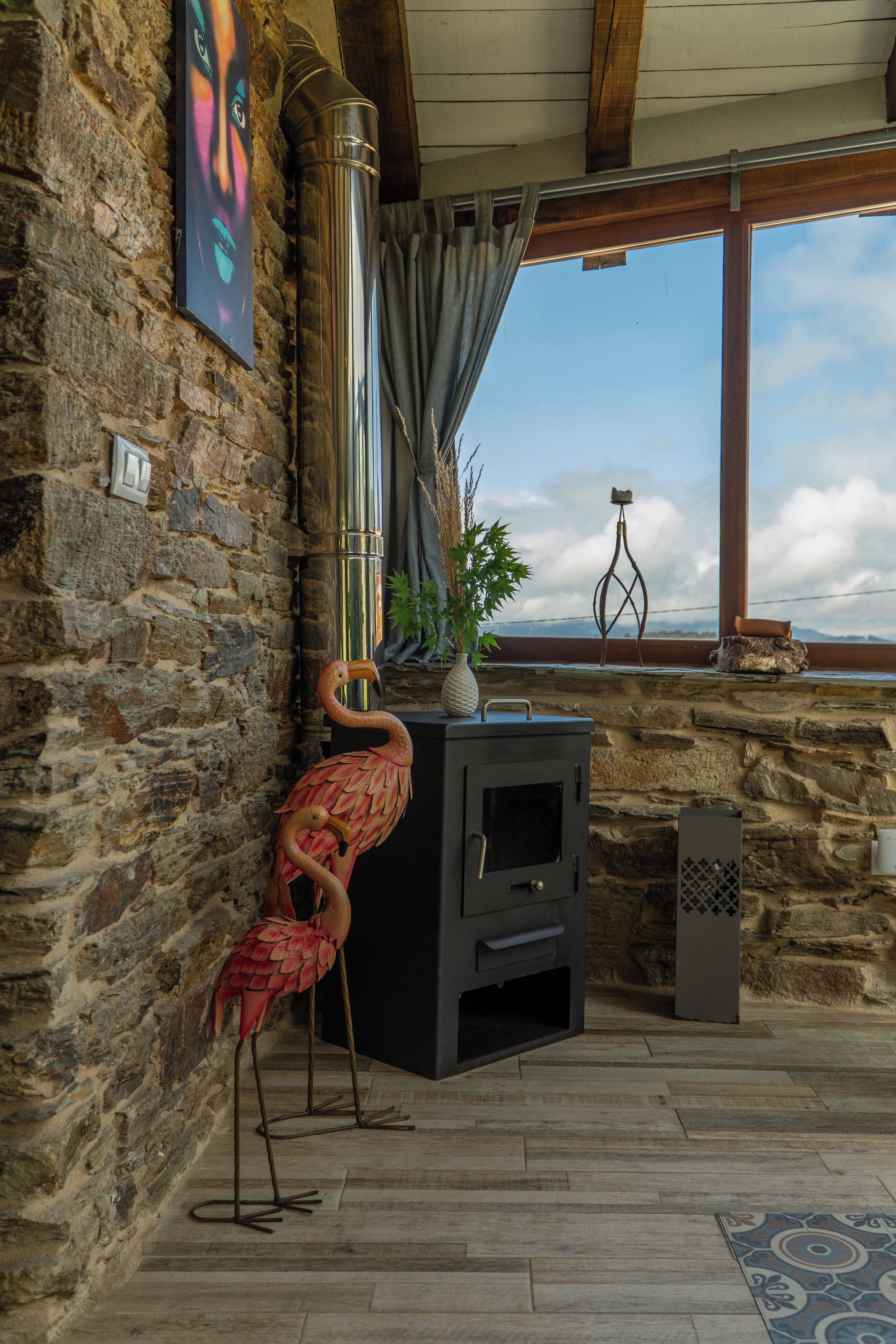 Un interior rústico con una pared de piedra, una chimenea y vistas a través de una ventana.