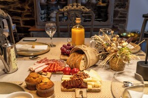 A breakfast table with various food items, a bottle of orange juice, and a rustic setting.