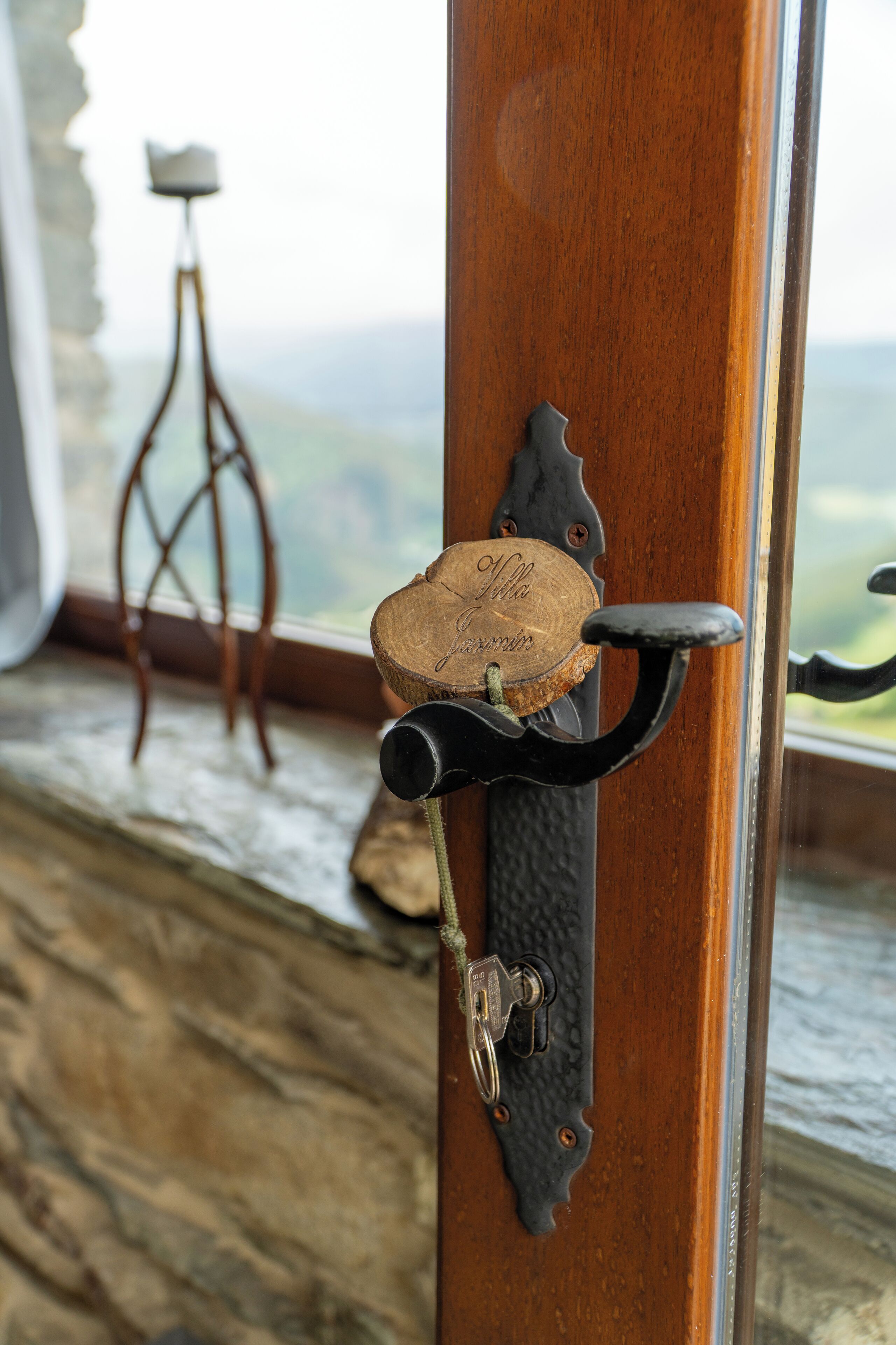A wooden door with a cork and metal hook, a keyhole, and a small wooden stool in the background.