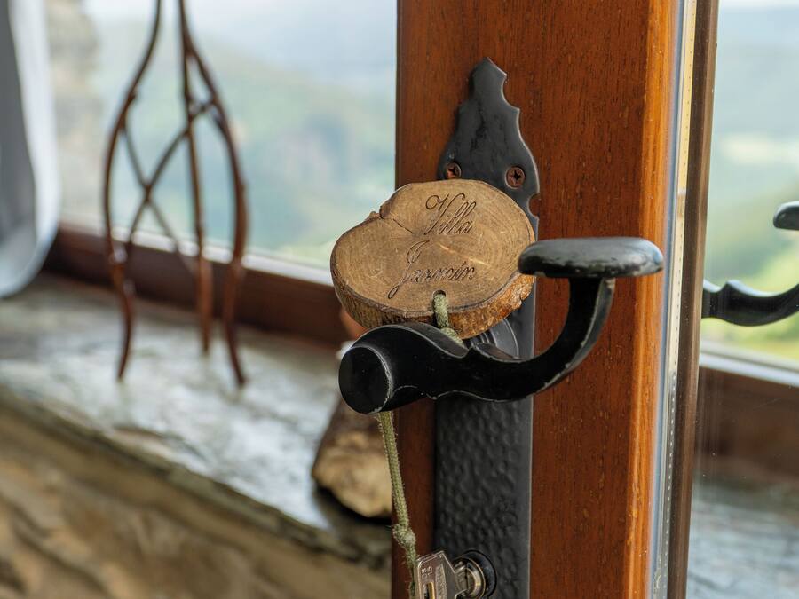 A wooden door with a cork and metal hook, a keyhole, and a small wooden stool in the background.