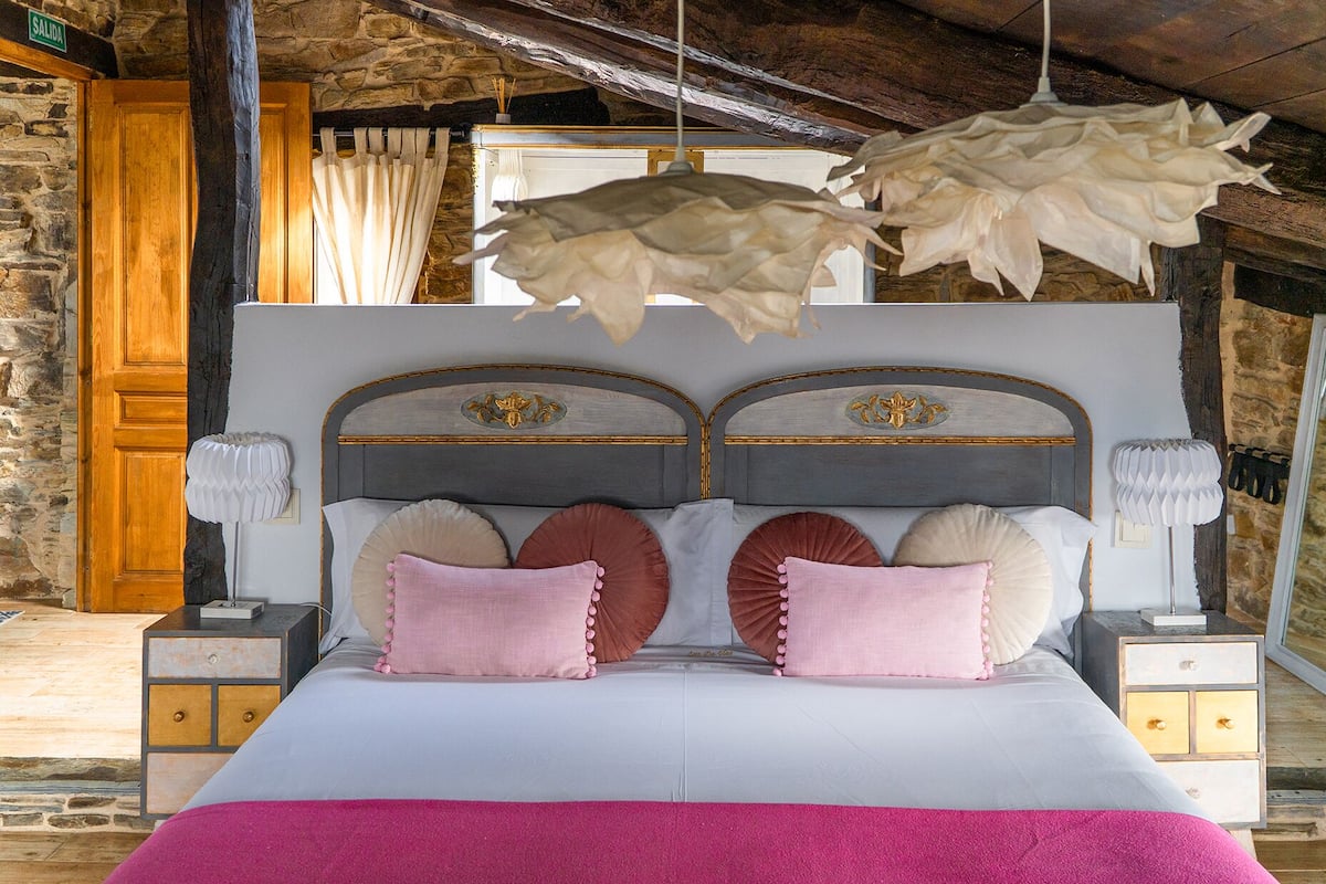 A bed with a white headboard, two nightstands, and a pink throw blanket.