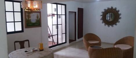 Una habitación con una mesa de comedor, sillas, un ventanal con vistas, un espejo y una lámpara colgante.