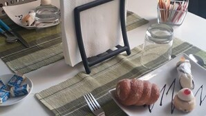 A dining table set with a plate of pastries, a fork, and a napkin holder. - B&B Dietro al Massimo (Palermo)