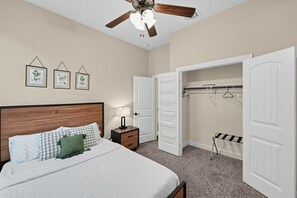 A bedroom with a bed, nightstand, closet, and ceiling fan.
