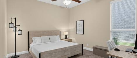 A bedroom with a bed, a desk with a computer, a ceiling fan, and a window with blinds.