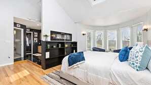 Une chambre à coucher avec un lit, une bibliothèque noire, un puits de lumière et une vue sur l’extérieur.