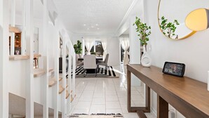 Un intérieur moderne comprenant un coin repas, un escalier et une horloge fixée au mur.