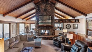 A spacious living room with a stone fireplace, leather furniture, and a high wooden ceiling. - Beautiful, large, private home in Fox Acres- huge patio w/ gorgeous views! (Red Feather Lakes)