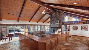 A spacious living area with a large wooden bar, stone fireplace, and a high ceiling with wooden beams. - Beautiful, large, private home in Fox Acres- huge patio w/ gorgeous views! (Red Feather Lakes)