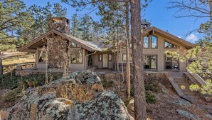 A modern house with a stone chimney, large windows, and a stone foundation. - Beautiful, large, private home in Fox Acres- huge patio w/ gorgeous views! (Red Feather Lakes)