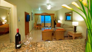 A hotel room with a dining area, a sofa, a TV, and a bottle of wine on the counter. - PARADISE VILLAGE RESORT 2 BEDROOM ONE WEEK MAX (Nuevo Vallarta)