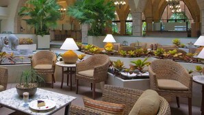 A spacious lobby with wicker furniture, a central fountain, and lush indoor plants. - PARADISE VILLAGE RESORT 2 BEDROOM ONE WEEK MAX (Nuevo Vallarta)