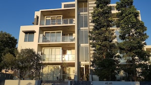 A modern multi-story residential building with balconies, large windows, and a gated entrance. - Perch Apartments at Anembo Street (Surfers Paradise)