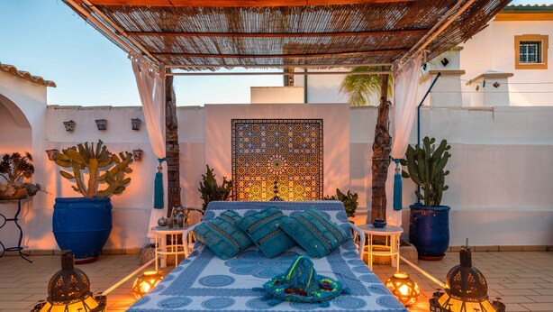 A bed with a patterned bedspread, surrounded by potted plants and lanterns, under a thatched roof structure. - Villa Oasis Galé - Luxury, private pool, AC, wifi and 5 mins from the beach (Albufeira, Faro)