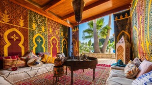 A room with intricate wall patterns, a wooden ceiling, a patterned rug, and a view of palm trees. - Villa Oasis Galé - Luxury, private pool, AC, wifi and 5 mins from the beach (Albufeira, Faro)