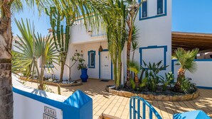 A courtyard with a blue and white building, palm trees, and a sign indicating room numbers. - Villa Oasis Galé - Luxury, private pool, AC, wifi and 5 mins from the beach (Albufeira, Faro)