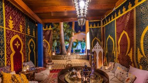 A room with intricate patterned walls, a central seating area with cushions, a coffee table, and a hanging light fixture. - Villa Oasis Galé - Luxury, private pool, AC, wifi and 5 mins from the beach (Albufeira, Faro)