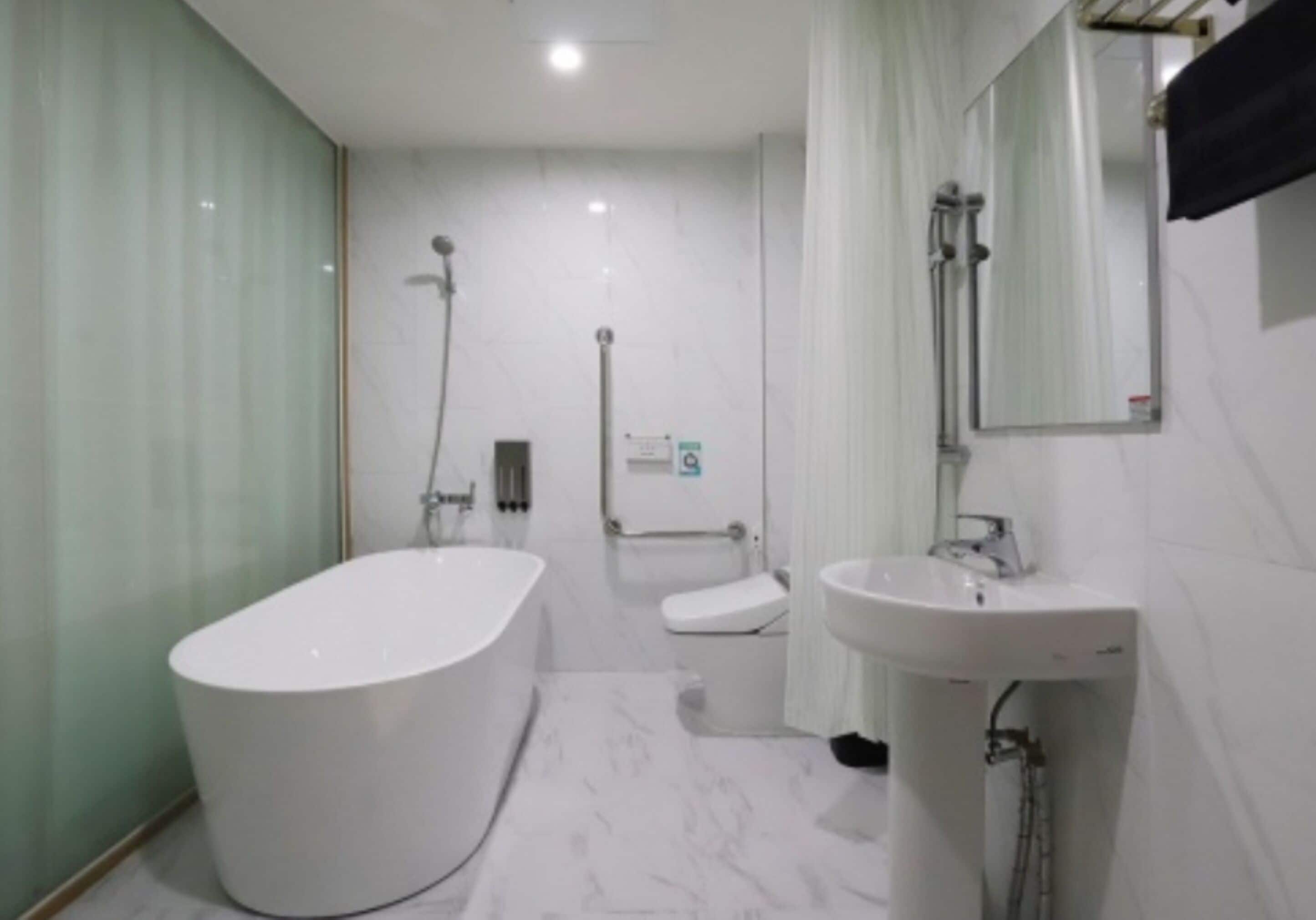 Un baño moderno con una bañera independiente, un inodoro y un lavamanos.