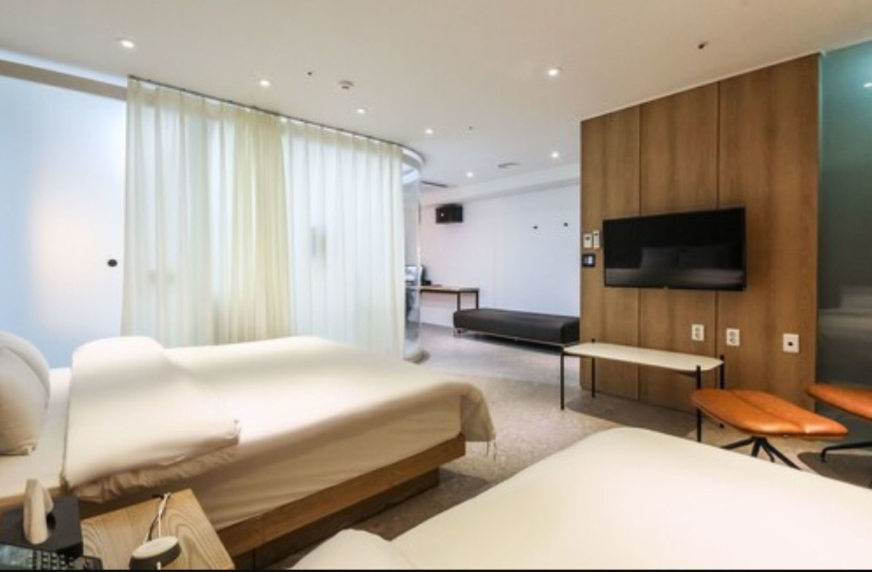 Une chambre d’hôtel moderne équipée de deux lits, d’un téléviseur à écran plat, d’un bureau et d’un banc.