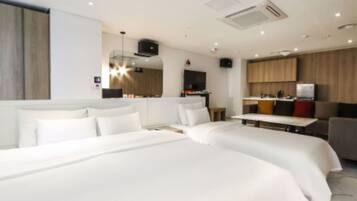 A hotel room with two beds, a kitchenette, and a seating area.