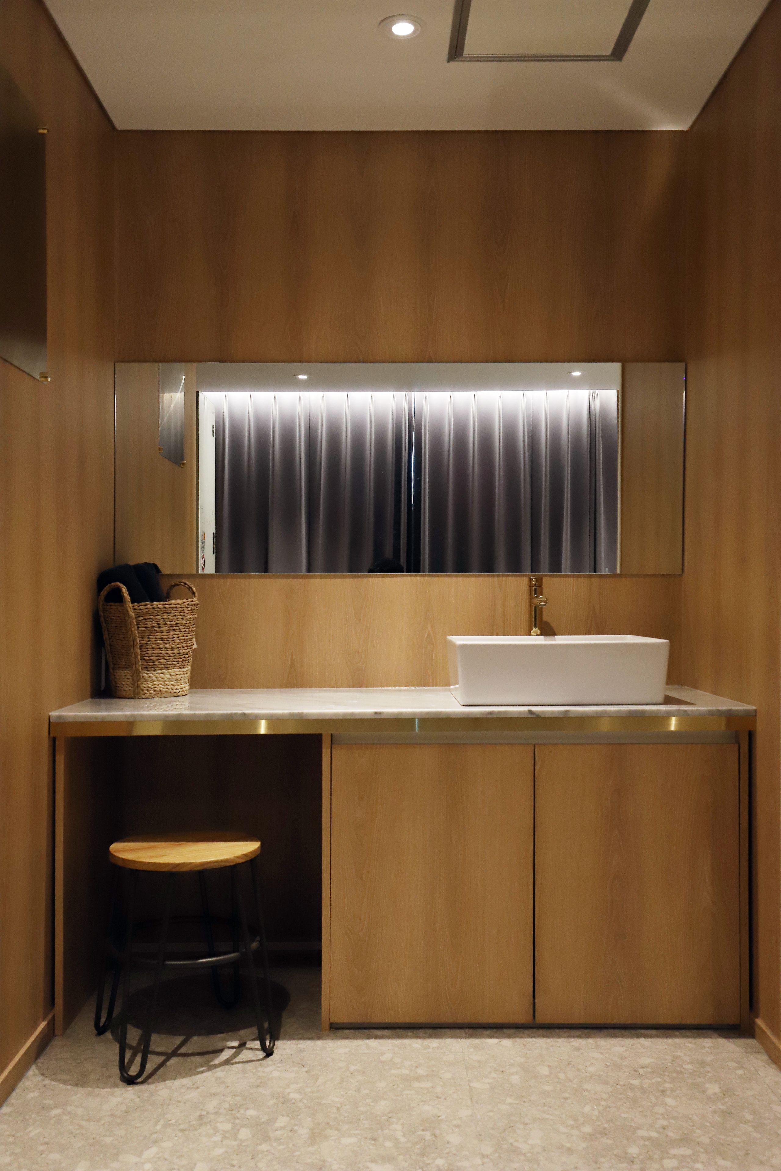 A modern bathroom with a wooden vanity, a white sink, and a mirror above it.