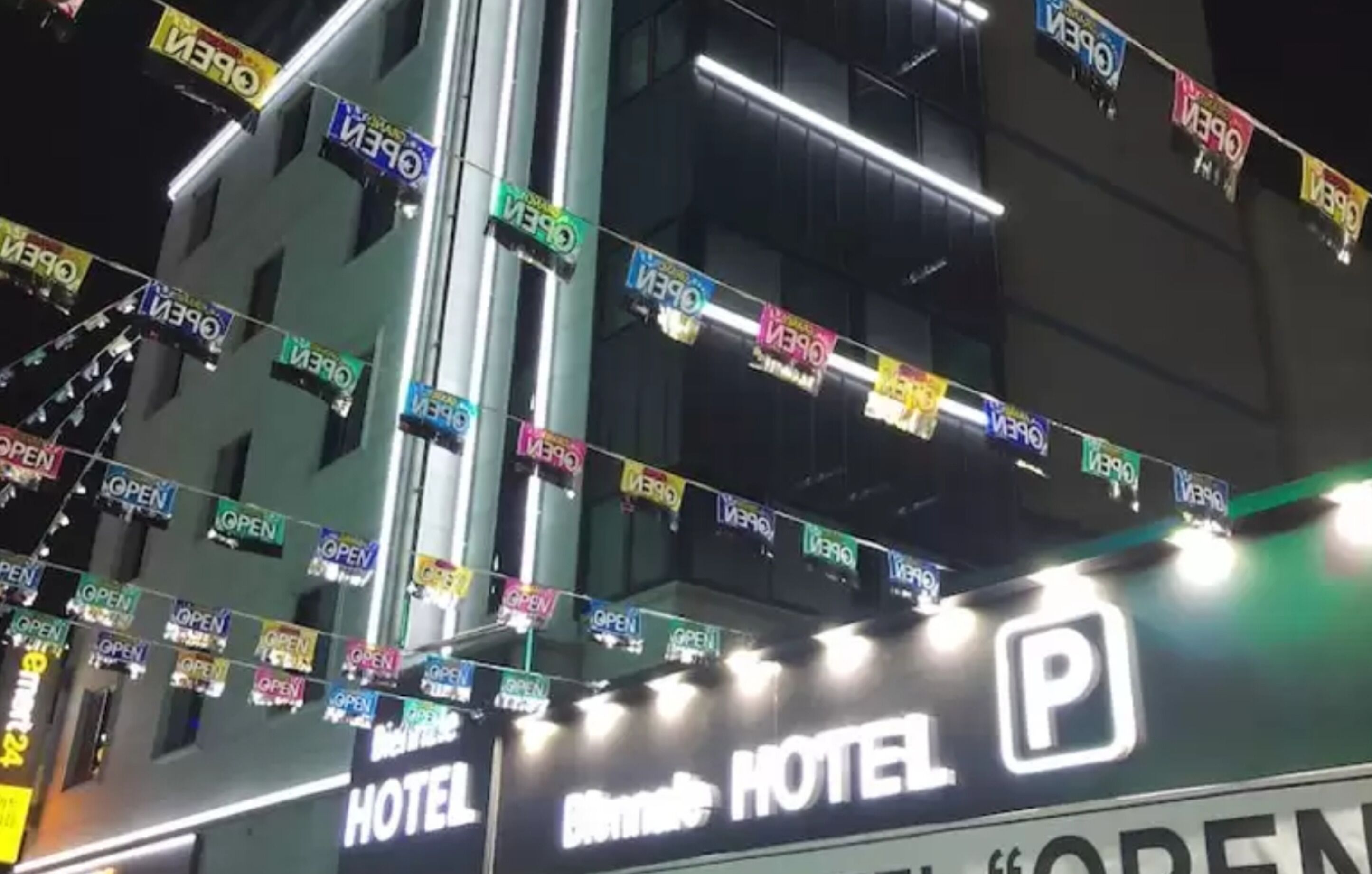 A hotel sign with multiple 'OPEN' banners and a parking sign.