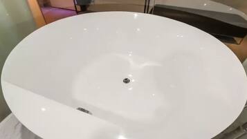 A large, round, white bathtub with a central drain.