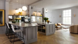 Una cocina amplia con una isla grande, taburetes de bar y un comedor con sofá y mesa de centro.