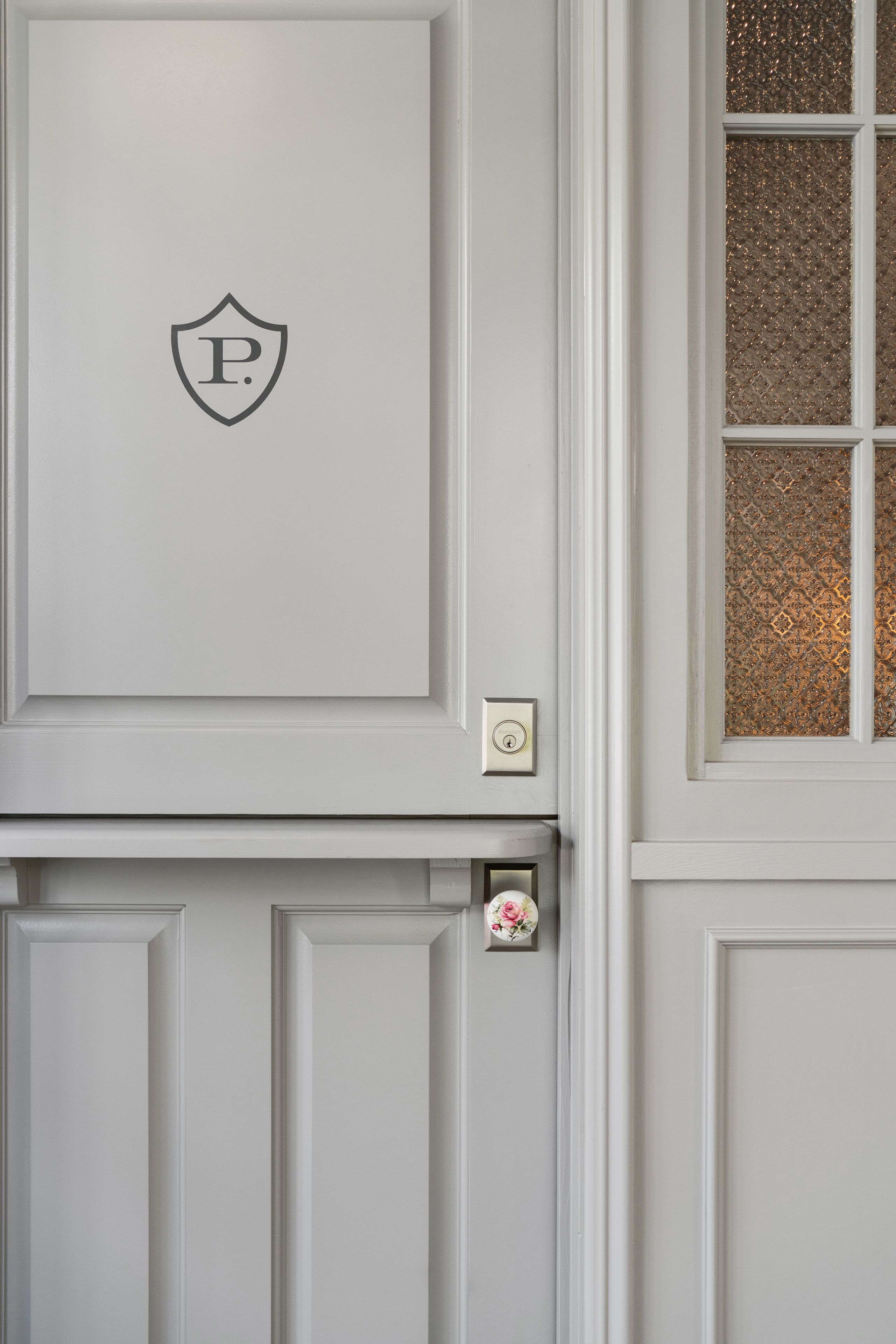 A white door with a shield-shaped emblem and a keyhole.