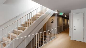 A hallway with a staircase, a door marked with the number 3, and an exit sign.