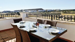 A dining table set for four on a balcony with wicker chairs, overlooking a golf course and residential buildings. - Lovely apartment in Sucina with swimming pool (Sucina)