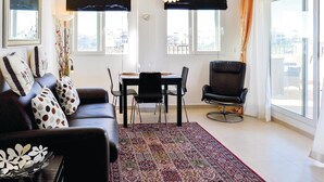 A modern living room with a black leather sofa, a dining table with chairs, a black armchair, and a patterned rug. - Lovely apartment in Sucina with swimming pool (Sucina)